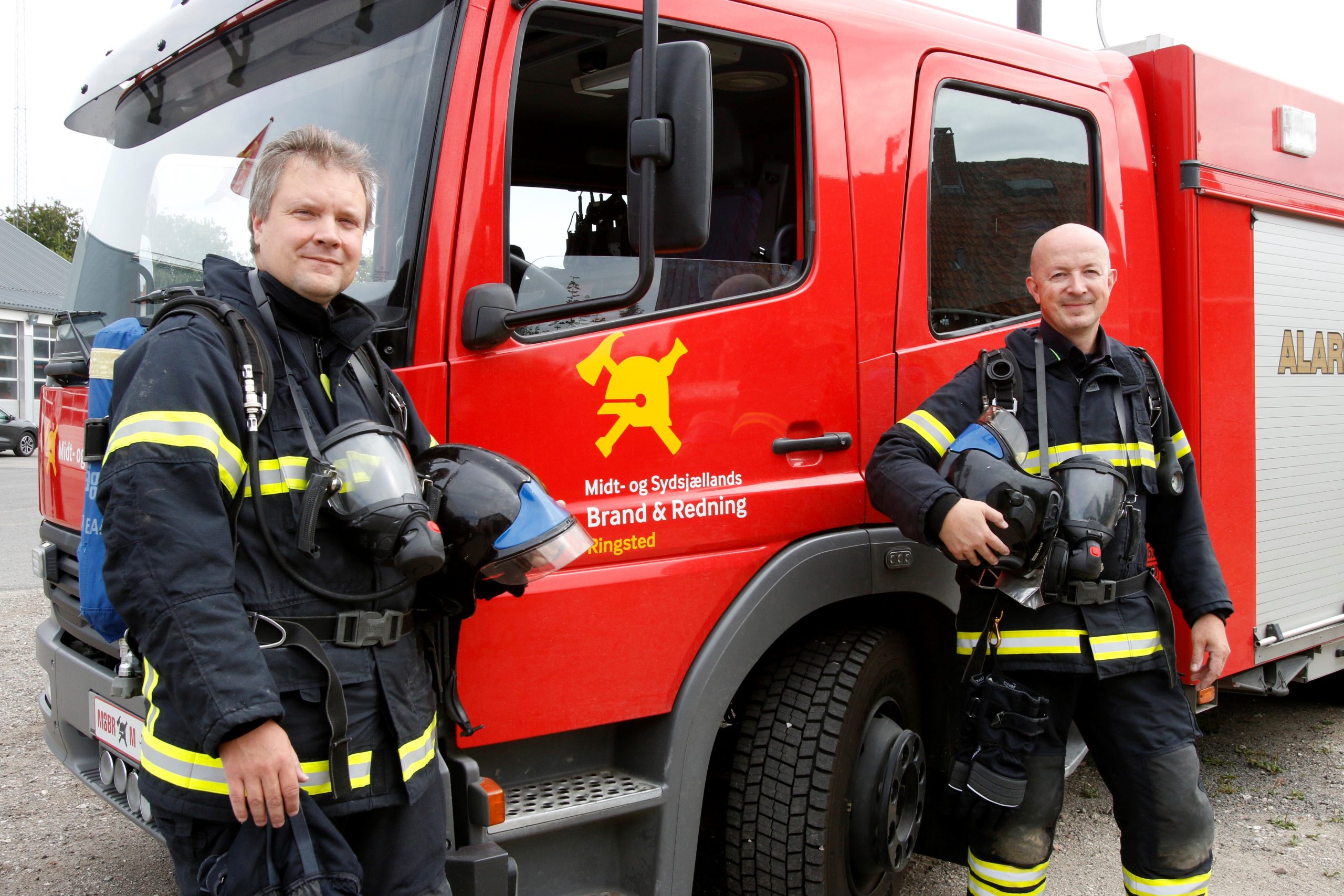 2 brandmænd foran en brandbil